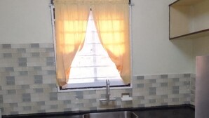 A kitchen with a sink, a window with curtains, and tiled backsplash. - 3 Bed House - Sleeps 4 - Parking - Enclosed Garden (Paramaribo)