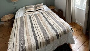A bedroom with a bed, two wall-mounted lamps, a woven tapestry, and a large window with curtains. - Very nice 4* listed Rhétaise house with garden and garage, quiet, right in the center, (Le Bois-Plage-en-Re)