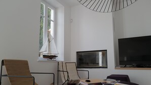 A modern living room with a sailboat model, a flat-screen TV, and a comfortable seating area. - Very nice 4* listed Rhétaise house with garden and garage, quiet, right in the center, (Le Bois-Plage-en-Re)