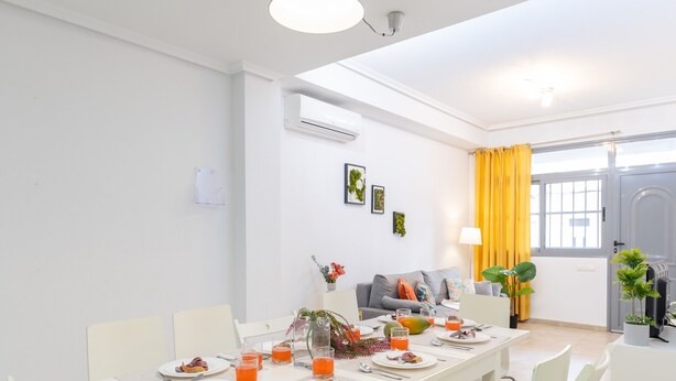 A dining area with a white table set for four, chairs, and pendant lighting. - Enjoy life in our apartment. Wifi & Parking (Guardamar)