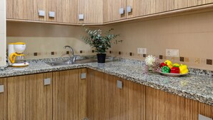 A kitchen with wooden cabinets, a granite countertop, a coffee maker, a sink, and a potted plant. - Enjoy life in our apartment. Wifi & Parking (Guardamar)