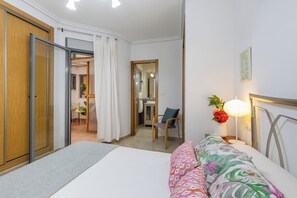 Een hotelkamer met een bed, een stoel, een bureau en een badkamer zichtbaar door een open deur.