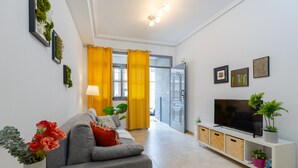 A modern living room with a grey sofa, a TV on a white cabinet, and a plant on the cabinet. - Enjoy life in our apartment. Wifi & Parking (Guardamar)