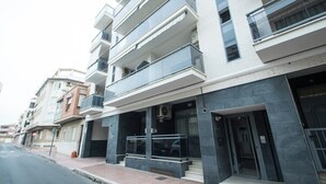 A multi-story residential building with balconies, a gated entrance, and a visible air conditioning unit. - Enjoy life in our apartment. Wifi & Parking (Guardamar)