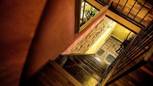 Puinen portaikko johtaa tasanteelle, jossa on kiviseinä ja ikkuna, jonka kautta näkyy hedelmiä.