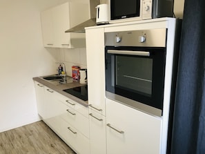 A modern kitchen with white cabinets, a built-in oven, and a microwave. - Generations Holiday Green View *King Size Bed* (Attendorn)