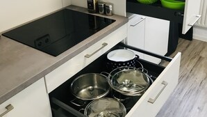 A modern kitchen with a black induction cooktop, white cabinets, and a built-in oven.