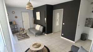 Un salon moderne avec un canapé gris, une table basse ronde et un mur d’accent noir.