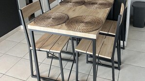 Une table à manger avec un set de table en fibres tressées, quatre chaises et un cadre en métal noir.