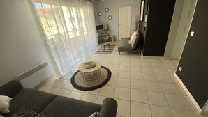 Un salon comprenant un canapé, une table basse, un téléviseur et un coin repas avec une table et des chaises.