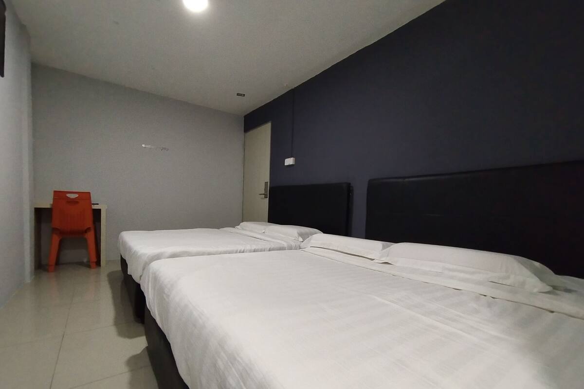 A room with two single beds, a chair, and a door.