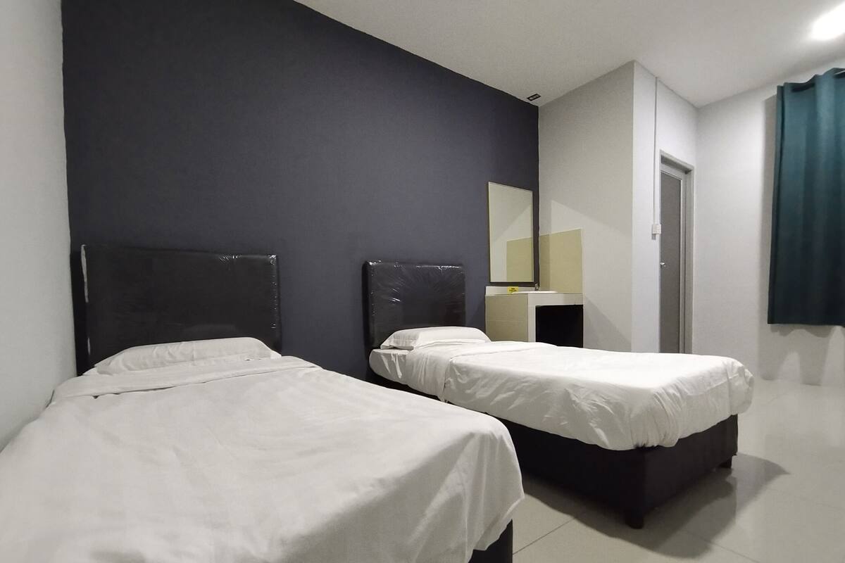 A hotel room with two beds, a dark-colored headboard, a mirror, and a door.