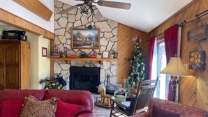 A cozy living room with a stone fireplace, a ceiling fan, and a Christmas tree. - Yellow Rose of Red River - In town, WIFI (Red River)