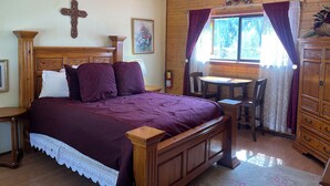 A wooden-framed bed with a cross on the wall, a painting, and a window with curtains. - Yellow Rose of Red River - In town, WIFI (Red River)