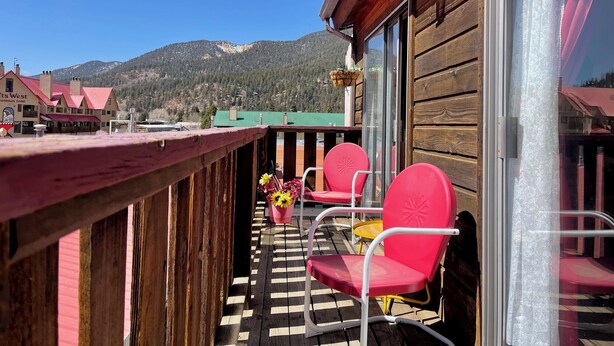 A wooden balcony with red chairs and a checkered floor, overlooking a mountain landscape. - Yellow Rose of Red River - In town, WIFI (Red River)