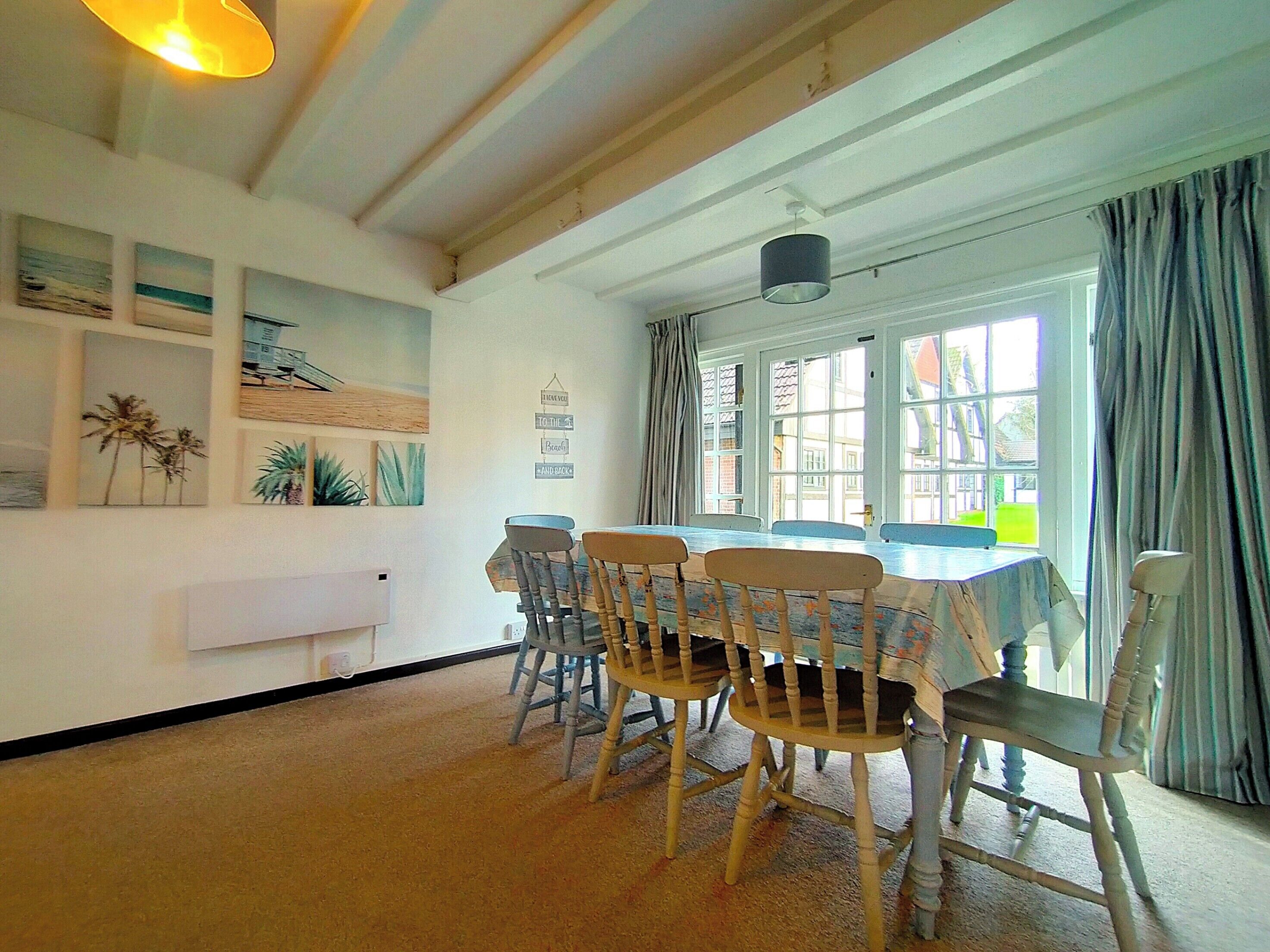 A dining area with a table and chairs, a ceiling light, and artwork on the walls.