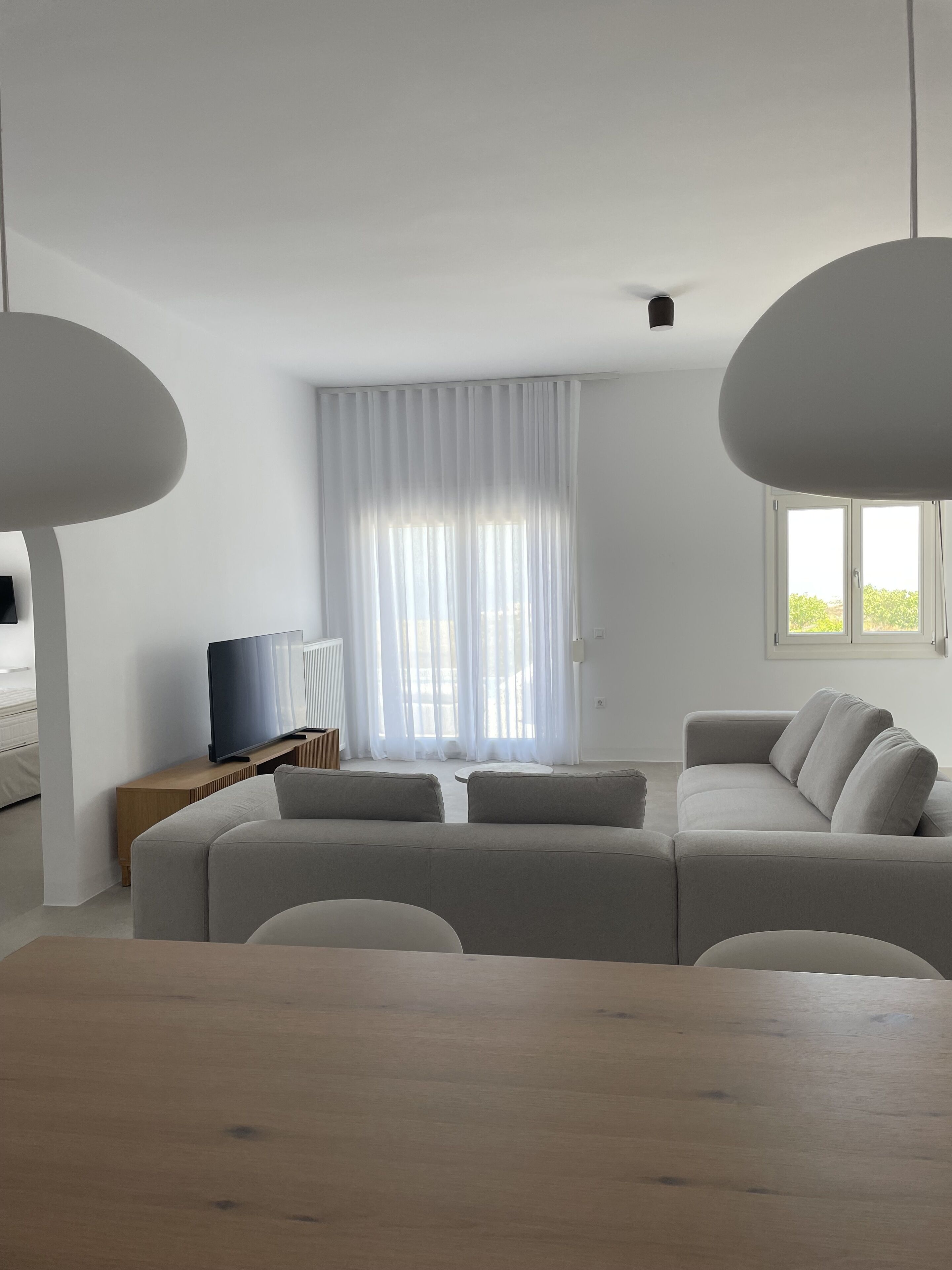 Ein modernes Wohnzimmer mit einer Eckcouch, einem Flachbildfernseher und einem Esstisch.