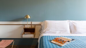 A hotel room with a bed, a nightstand, a lamp, and a magazine on the bed. - Hotel Millepini (Ravenna)