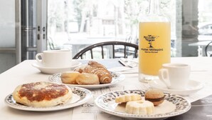 A breakfast table with croissants, muffins, and a bottle of orange juice. - Hotel Millepini (Ravenna)