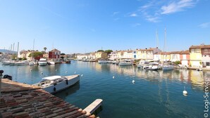 A marina with boats docked, a red building, and colorful houses along the waterfront.
