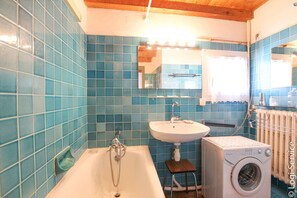 Ein Badezimmer mit Badewanne, Waschbecken und Waschmaschine.
