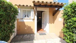 A narrow entrance with a tiled roof, a door, and a small window with shutters.