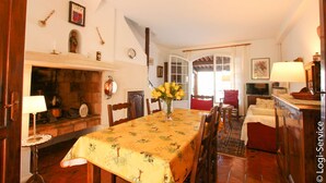 A dining room with a table set for four, a fireplace, and a view into the adjacent room.