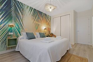 A bedroom with a bed, bedside lamps, a wall mural, and a door. - Butibamba apartment pool view (La Cala de Mijas)