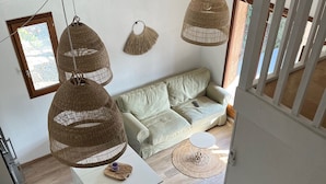 Een moderne woonkamer met een bank, een salontafel en hangende rieten lampen.