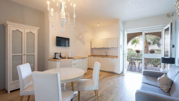 A modern kitchen with white cabinets and a dining area with a round table and white chairs. - Don Onofrio Holiday House - app.to Domitilla (Monopoli)