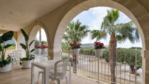 A balcony with white chairs and tables, potted plants, and a view of palm trees and mountains. - Don Onofrio Holiday House - app.to Domitilla (Monopoli)