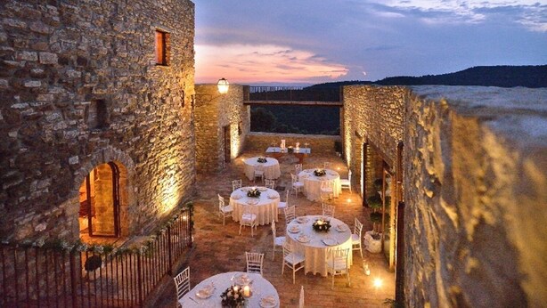 An outdoor dining area with stone walls and tables set for a meal, overlooking a scenic landscape. - Tenuta di Forte Sorgnano | Farmhouse with private pool (Gualdo Cattaneo (PG))