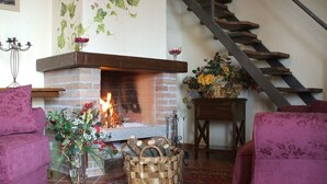 A cozy living room with a fireplace, a staircase, and floral decorations. - Tenuta di Forte Sorgnano | Farmhouse with private pool (Gualdo Cattaneo (PG))