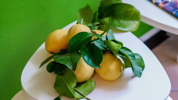 A white table with a plate of lemons and leaves.