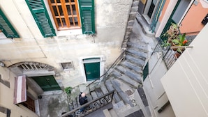 Un estrecho callejón con una escalera de piedra que lleva a una puerta con un persiano verde.
