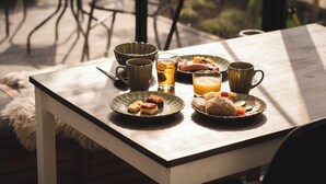 Una mesa de desayuno con platos de comida, tazas y un vaso de jugo.