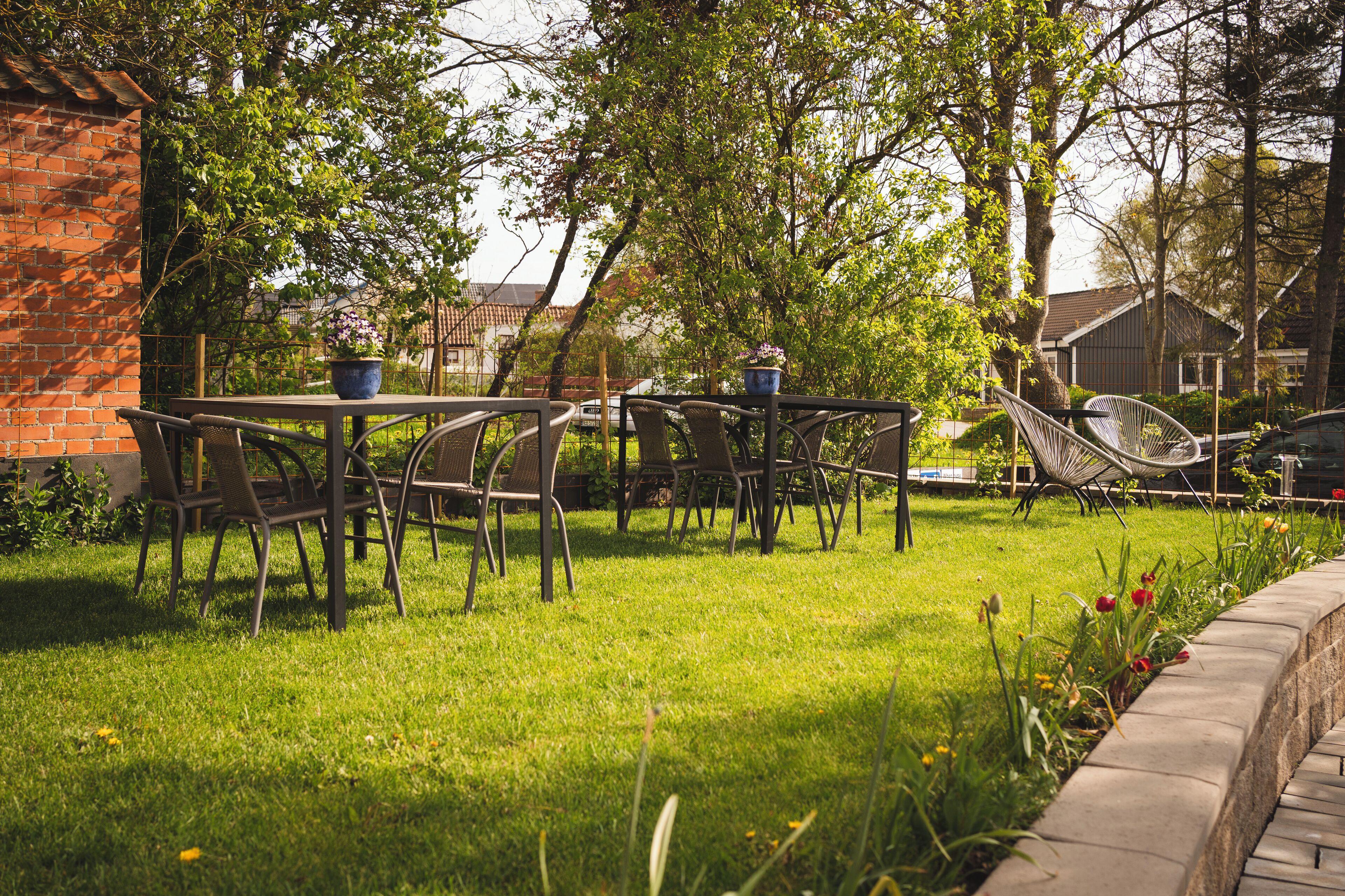 Eine Terrasse mit Tisch und Stühlen, umgeben von einer Ziegelmauer und Pflanzen.
