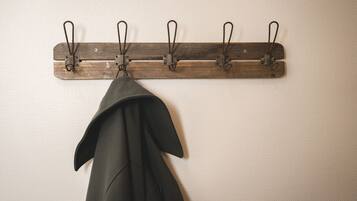 A wooden coat rack with four hooks against a textured wall.