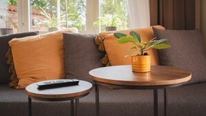 Una sala de estar moderna con un sofá, una mesa redonda de madera y una planta en maceta.