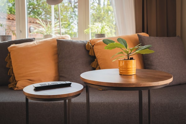 Una sala de estar moderna con un sofá, una mesa redonda de madera y una planta en maceta.