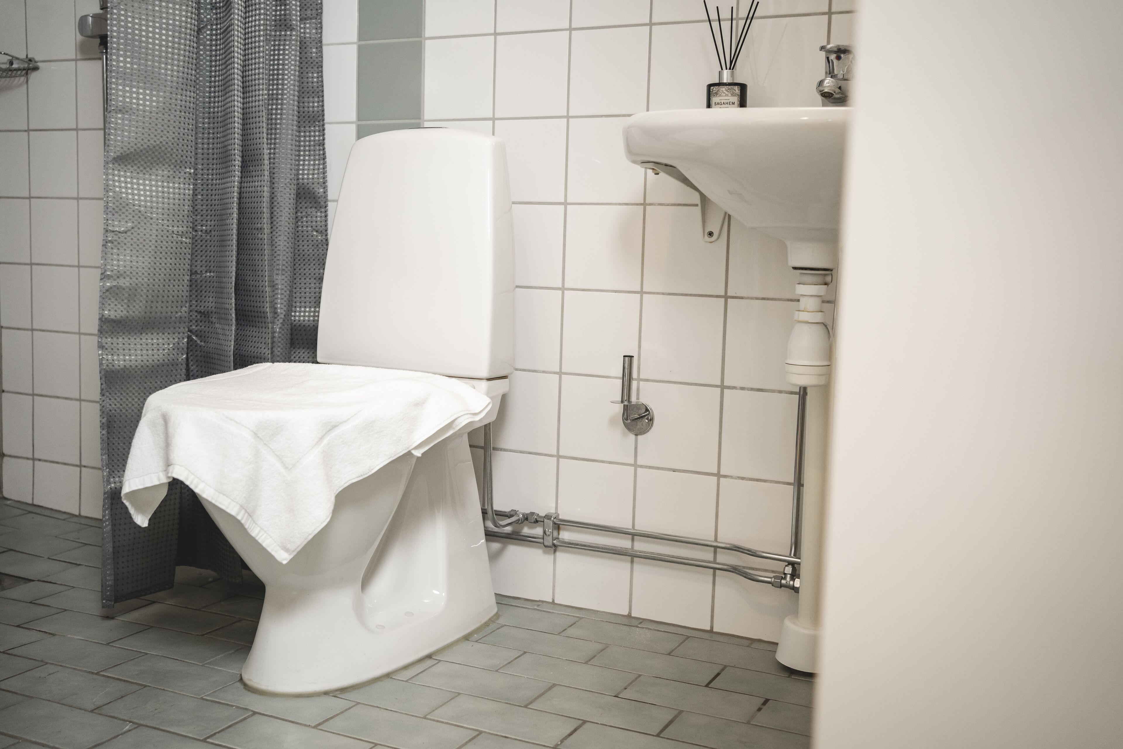 A bathroom with a toilet, a shower curtain, and a sink.