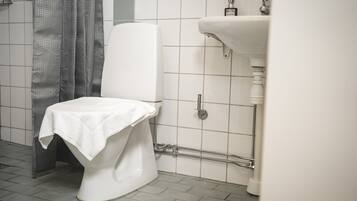 A bathroom with a toilet, a shower curtain, and a sink.