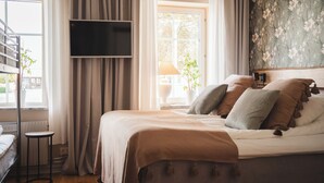 Un dormitorio con cama, cortinas, televisor, ventana y una planta.