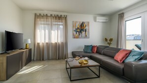 A modern living room with a sectional sofa, a flat-screen TV, a coffee table, and a painting on the wall. - Villa Dora - Apartment 4 "Brown" with balcony (Pula)