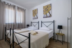 Een hotelkamer met twee bedden, een kleine tafel en twee schilderijen aan de muur.