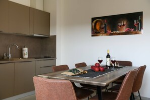 Een moderne keuken met een eettafel voor vier personen, compleet met een wijnfles, glazen en appels.