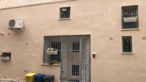 A building with a beige exterior, a metal gate, and a small window with a flower box. There are three trash bins in front. - Il loft del vico - Salento (galatone)