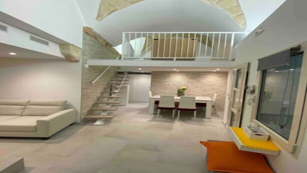 A modern interior with a dining area, staircase, and a balcony. - Il loft del vico - Salento (galatone)