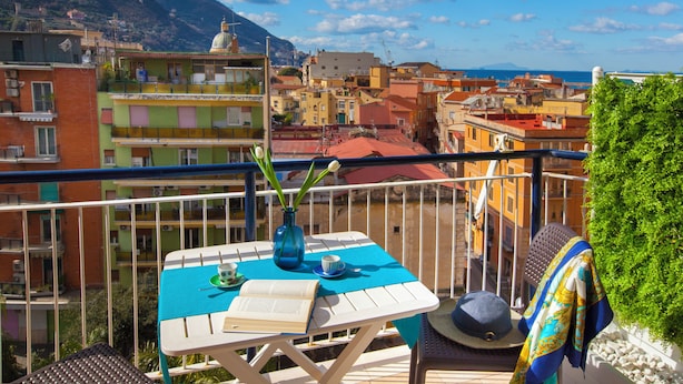 A balcony with a table, a book, a vase with flowers, and a hat. - Shabby Chic sea view apartment (Castellammare di Stabia)
