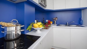 A modern kitchen with white cabinets, a black induction cooktop, and a blue accent wall. - Shabby Chic sea view apartment (Castellammare di Stabia)